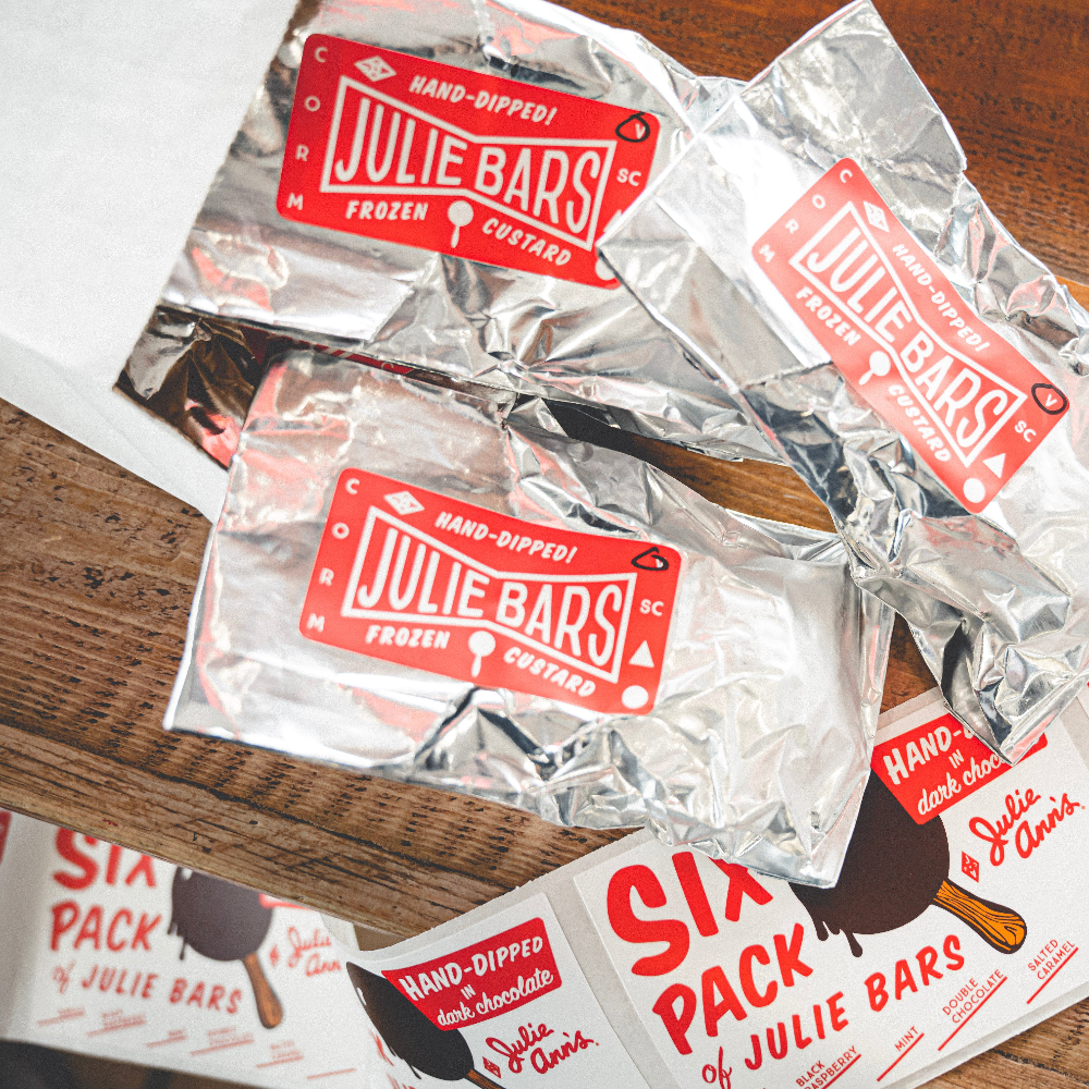 Julie Bars ice cream packages on a wooden surface with additional packaging in the background.