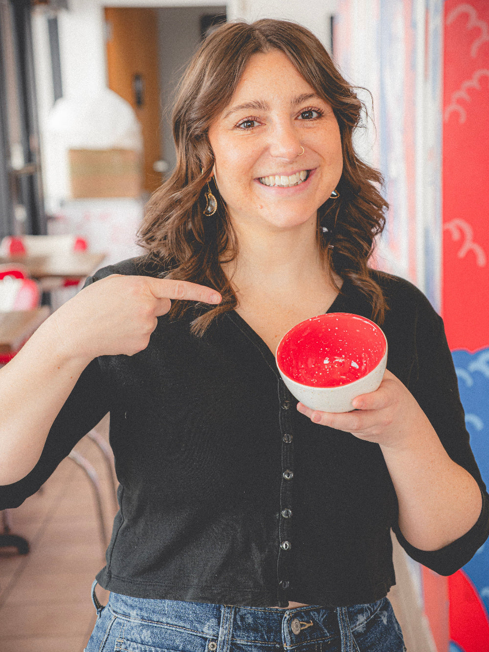 Woman holding a red and white spherical object in a casual indoor setting