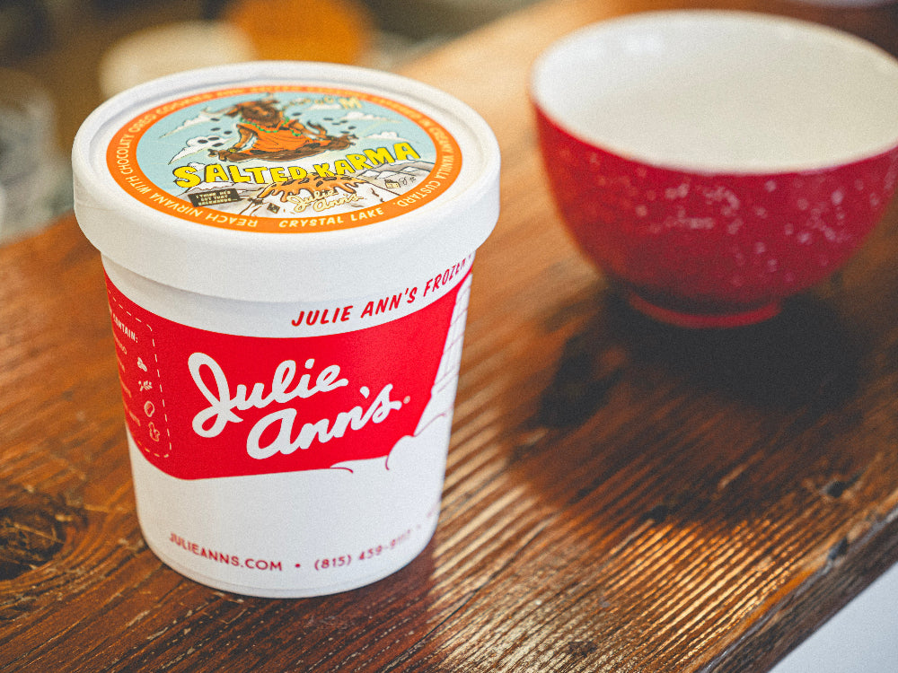 Container of Julie Ann's ice cream with a red lid on a wooden surface