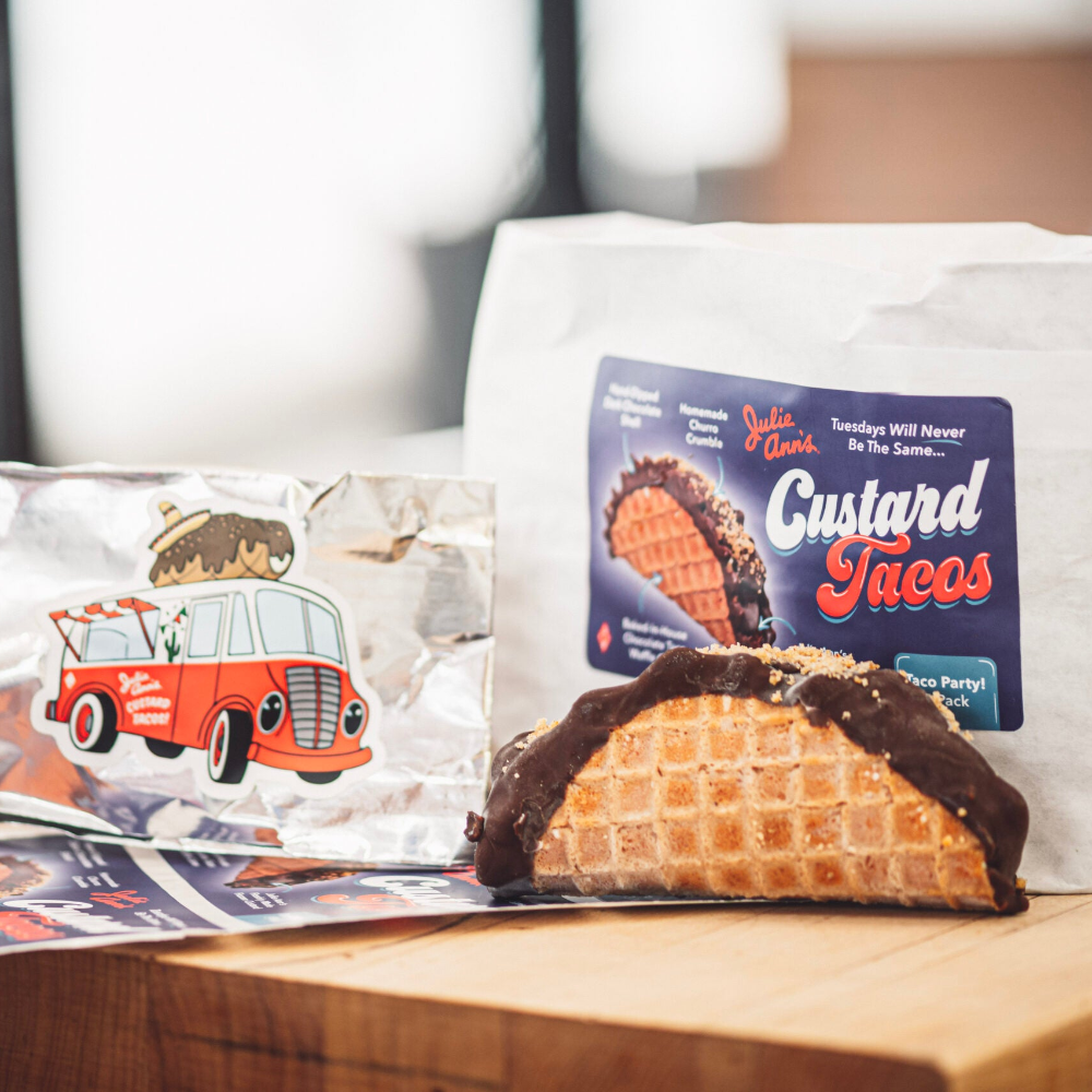 Custard taco with chocolate drizzle on a table next to a magazine featuring a red bus illustration.