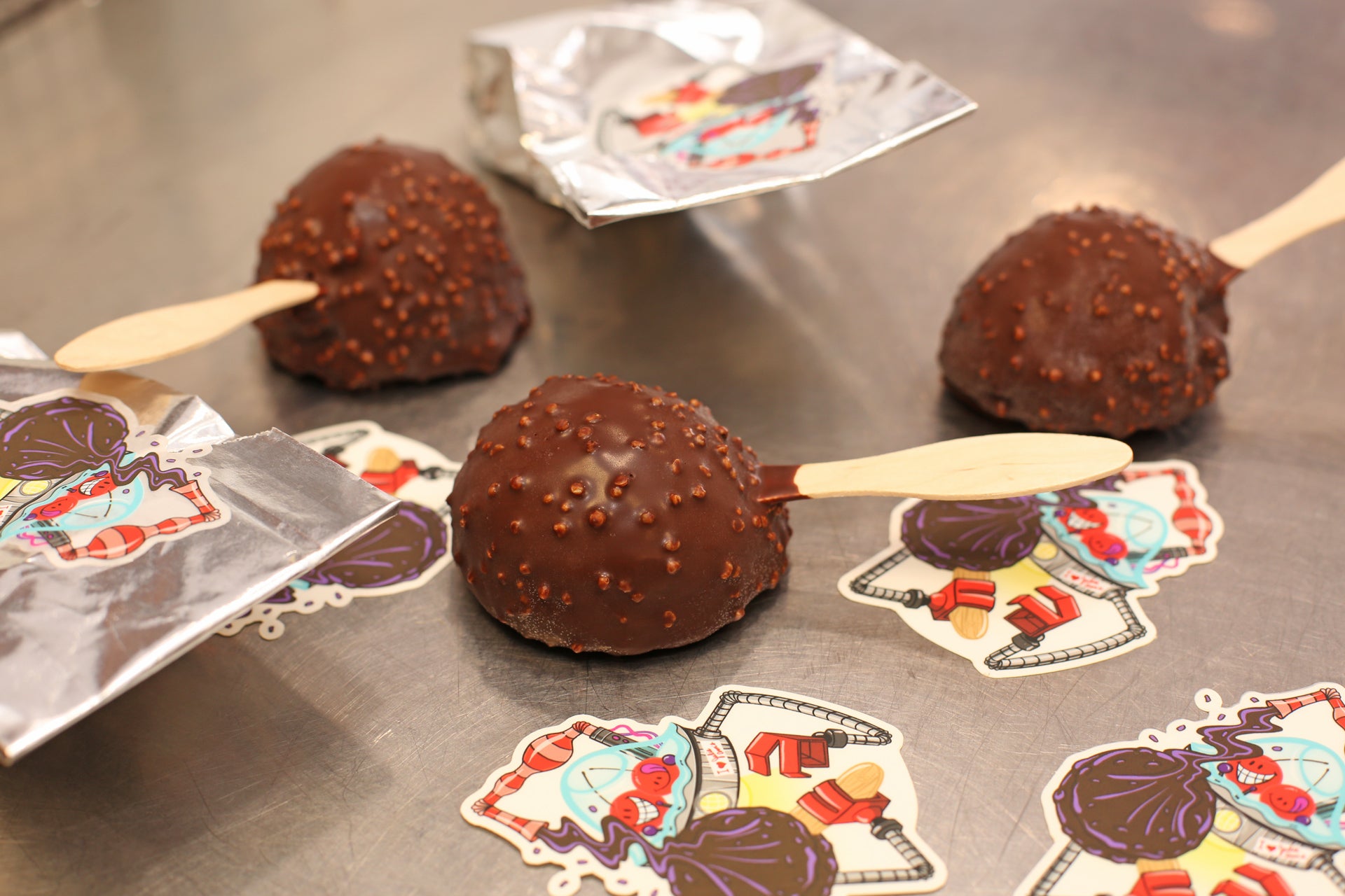 Chocolate crunch bars on sticks with colorful paper decorations on a metallic surface