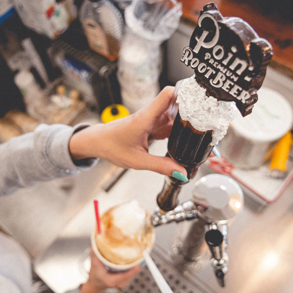 Person pouring root beer from a tap into a root beer float.