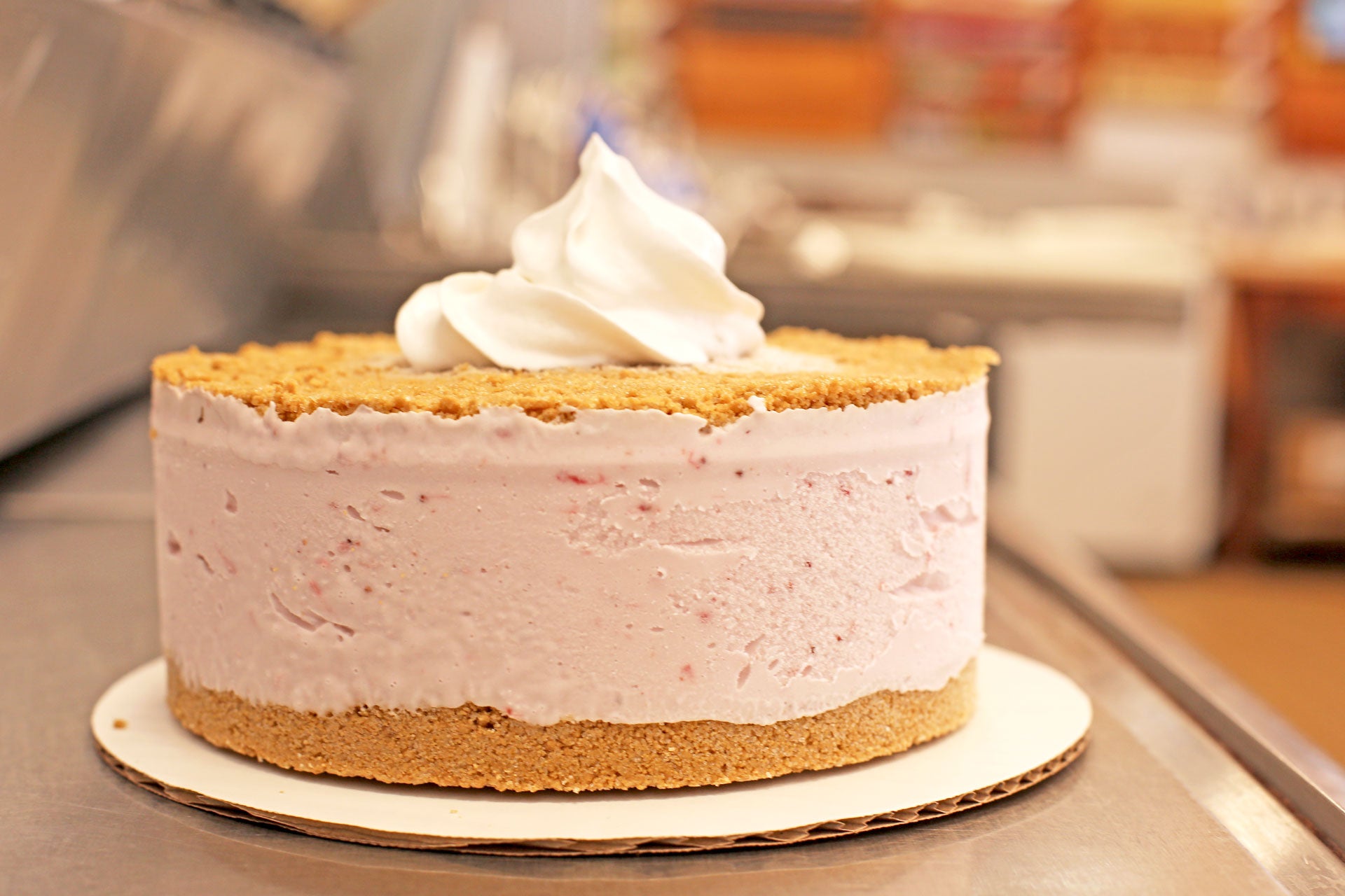 dairy-free cake with a gluten-free graham cracker crust and non-dairy whipped cream on a counter.